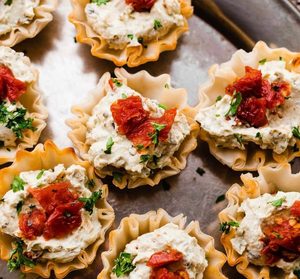 Mini phyllo cups filled with creamy cheese and topped with chopped tomatoes and parsley.